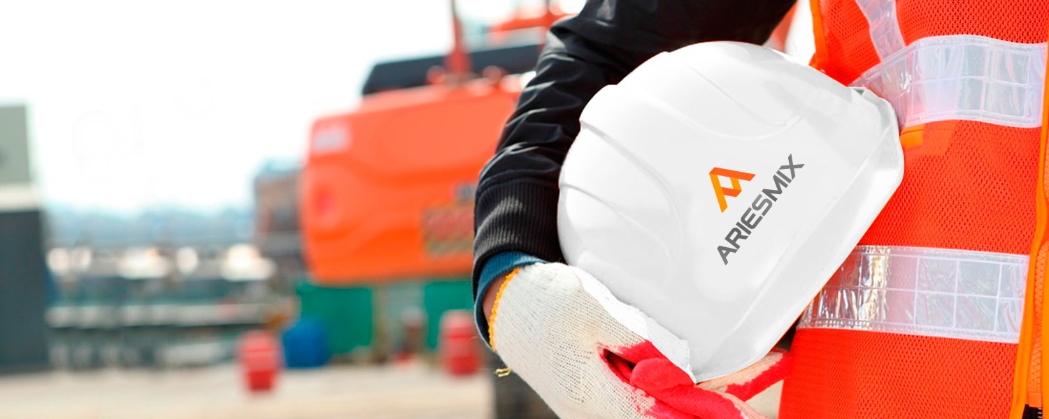 Trabajador con casco blanco y chaleco naranja de AriesMix en una obra
